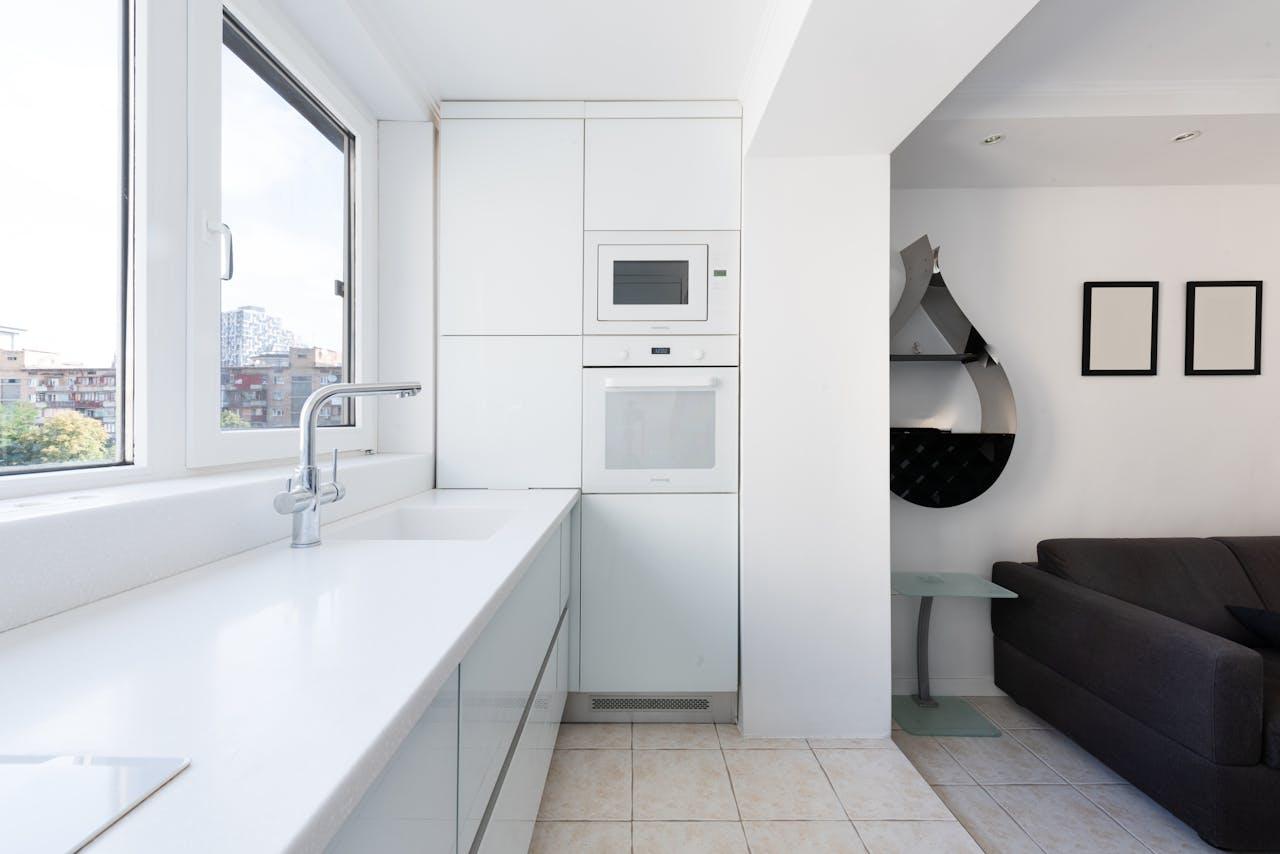 A bright and contemporary kitchen area with sleek white cabinets and integrated appliances.